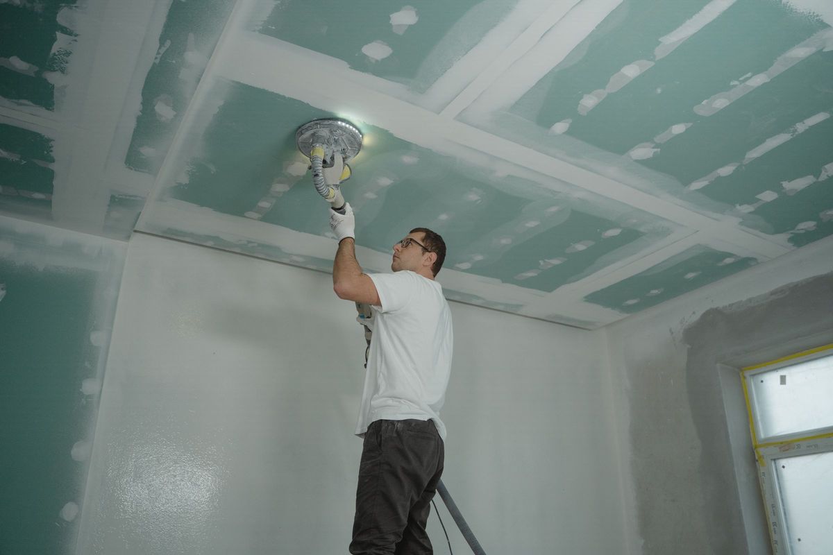 Een plafond van gipsplaten wordt na het voegen glad geschuurd